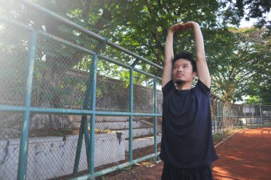 Bir adam çitin önünde kolunu uzatıyor. Kararlılık kavramı ve adam esnekliği üzerinde çalışırken odaklanma.