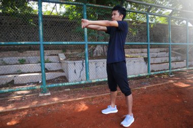 Bir adam çitin önünde kolunu uzatıyor. Kararlılık kavramı ve adam esnekliği üzerinde çalışırken odaklanma.