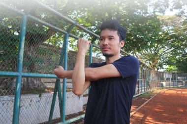 Bir adam çitin önünde kolunu uzatıyor. Kararlılık kavramı ve adam esnekliği üzerinde çalışırken odaklanma.