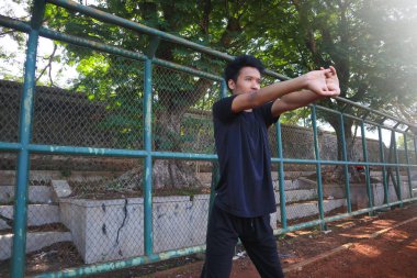 Bir adam çitin önünde kolunu uzatıyor. Kararlılık kavramı ve adam esnekliği üzerinde çalışırken odaklanma.