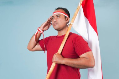 Endonezya 'nın Bağımsızlık Günü konsepti, saygılı bir şekilde poz verirken elinde bayrak tutan enerjik genç bir Endonezyalı..