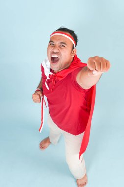 Sırtına ülke bayrağı takmış mutlu Endonezyalı genç bir adam ve el yapımı süper kahraman sineği hareketi. Endonezya Bağımsızlık Günü kavramı.