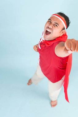 Sırtına ülke bayrağı takmış mutlu Endonezyalı genç bir adam ve el yapımı süper kahraman sineği hareketi. Endonezya Bağımsızlık Günü kavramı.