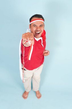 Sırtına ülke bayrağı takmış mutlu Endonezyalı genç bir adam ve el yapımı süper kahraman sineği hareketi. Endonezya Bağımsızlık Günü kavramı.