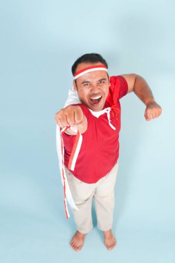 Sırtına ülke bayrağı takmış mutlu Endonezyalı genç bir adam ve el yapımı süper kahraman sineği hareketi. Endonezya Bağımsızlık Günü kavramı.