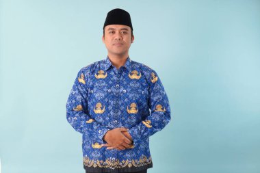 Kıs kıs gülen devlet memuru, mavi batik üniforma giyiyor. Bir PNS filmi için poz veriyor. ASN devlet memuru konsepti..