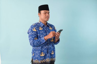 Kopri Blue Batik üniforması giyen gülümseyen devlet çalışanı akıllı telefonunu işaret ederken görüntülü arama yapıyor. PNS, ASN memur konsepti.