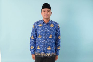 Kıs kıs gülen devlet memuru, mavi batik üniforma giyiyor. Bir PNS filmi için poz veriyor. ASN devlet memuru konsepti..