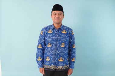 Kıs kıs gülen devlet memuru, mavi batik üniforma giyiyor. Bir PNS filmi için poz veriyor. ASN devlet memuru konsepti..