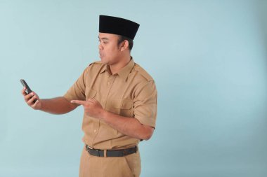 Haki üniformalı gülümseyen devlet memuru akıllı telefonuna, ASN devlet memuru konseptine işaret ederken video çağrısı yapıyor..