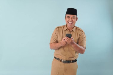 Haki üniformalı gülümseyen devlet memuru akıllı telefonuna, ASN devlet memuru konseptine işaret ederken video çağrısı yapıyor..