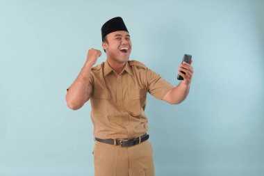 Haki üniformalı gülümseyen devlet memuru akıllı telefonuna, ASN devlet memuru konseptine işaret ederken video çağrısı yapıyor..