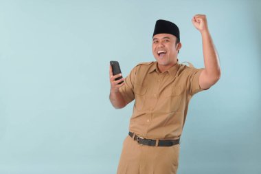 Haki üniformalı gülümseyen devlet memuru akıllı telefonuna, ASN devlet memuru konseptine işaret ederken video çağrısı yapıyor..