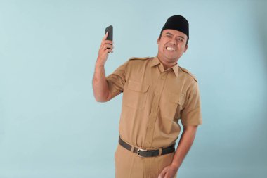 Hükümet çalışanı cep telefonuyla konuşuyor. Gülümsüyor ve PNS 'nin tadını çıkarıyor, ASN devlet memuru konsepti. Yüzüne bir cep telefonu dayadılar..