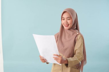 Haki üniformalı gülümseyen devlet memuru elinde PNS, ASN devlet memuru konsepti gibi poz veren bir belge tutuyor..