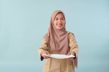 Haki üniformalı gülümseyen devlet memuru elinde PNS, ASN devlet memuru konsepti gibi poz veren bir belge tutuyor..