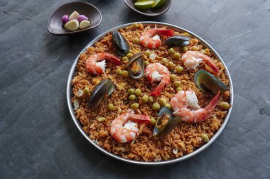 Paella, pirinç, deniz ürünleri, karides, istiridye, limon ve safran soslu bezelye karışımı bir İspanyol yemeğidir..
