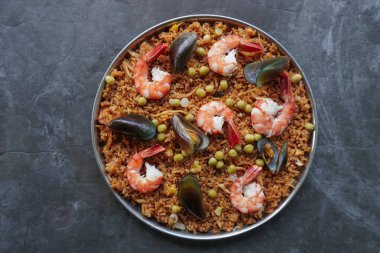 Paella, pirinç, deniz ürünleri, karides, istiridye, limon ve safran soslu bezelye karışımı bir İspanyol yemeğidir..