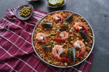Paella, pirinç, deniz ürünleri, karides, istiridye, limon ve safran soslu bezelye karışımı bir İspanyol yemeğidir..
