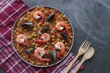 Paella, pirinç, deniz ürünleri, karides, istiridye, limon ve safran soslu bezelye karışımı bir İspanyol yemeğidir..