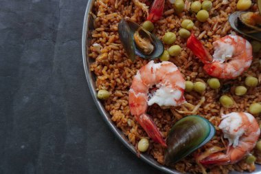 Paella, pirinç, deniz ürünleri, karides, istiridye, limon ve safran soslu bezelye karışımı bir İspanyol yemeğidir..