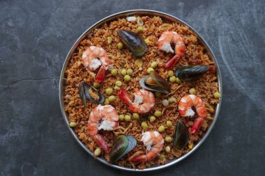 Paella, pirinç, deniz ürünleri, karides, istiridye, limon ve safran soslu bezelye karışımı bir İspanyol yemeğidir..
