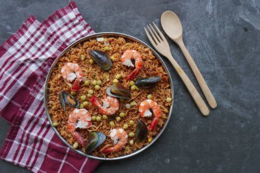 Paella, pirinç, deniz ürünleri, karides, istiridye, limon ve safran soslu bezelye karışımı bir İspanyol yemeğidir..