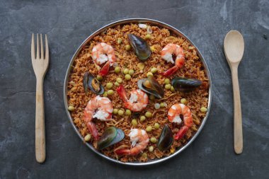 Paella, pirinç, deniz ürünleri, karides, istiridye, limon ve safran soslu bezelye karışımı bir İspanyol yemeğidir..
