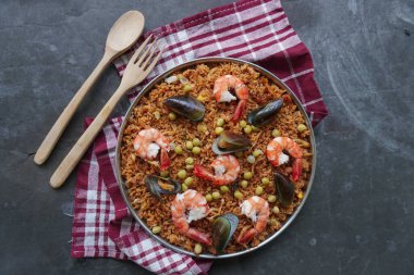Paella, pirinç, deniz ürünleri, karides, istiridye, limon ve safran soslu bezelye karışımı bir İspanyol yemeğidir..