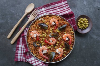 Paella, pirinç, deniz ürünleri, karides, istiridye, limon ve safran soslu bezelye karışımı bir İspanyol yemeğidir..