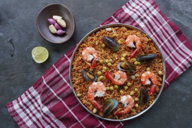 Paella, pirinç, deniz ürünleri, karides, istiridye, limon ve safran soslu bezelye karışımı bir İspanyol yemeğidir..