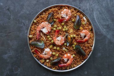 Paella, pirinç, deniz ürünleri, karides, istiridye, limon ve safran soslu bezelye karışımı bir İspanyol yemeğidir..