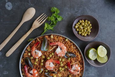 Paella, pirinç, deniz ürünleri, karides, istiridye, limon ve safran soslu bezelye karışımı bir İspanyol yemeğidir..