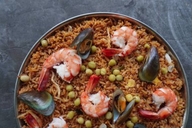 Paella, pirinç, deniz ürünleri, karides, istiridye, limon ve safran soslu bezelye karışımı bir İspanyol yemeğidir..