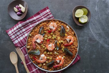 Paella, pirinç, deniz ürünleri, karides, istiridye, limon ve safran soslu bezelye karışımı bir İspanyol yemeğidir..