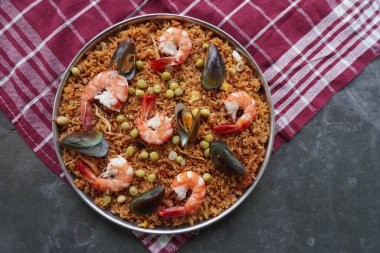 Paella, pirinç, deniz ürünleri, karides, istiridye, limon ve safran soslu bezelye karışımı bir İspanyol yemeğidir..