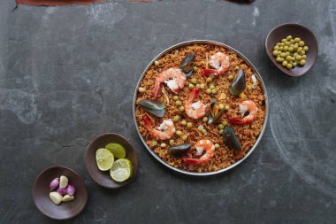 Paella, pirinç, deniz ürünleri, karides, istiridye, limon ve safran soslu bezelye karışımı bir İspanyol yemeğidir..
