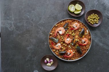 Paella, pirinç, deniz ürünleri, karides, istiridye, limon ve safran soslu bezelye karışımı bir İspanyol yemeğidir..