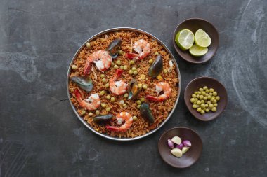 Paella, pirinç, deniz ürünleri, karides, istiridye, limon ve safran soslu bezelye karışımı bir İspanyol yemeğidir..
