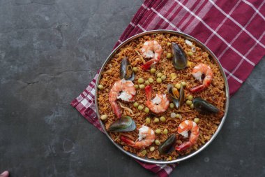 Paella, pirinç, deniz ürünleri, karides, istiridye, limon ve safran soslu bezelye karışımı bir İspanyol yemeğidir..