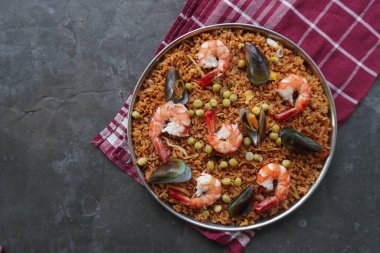 Paella, pirinç, deniz ürünleri, karides, istiridye, limon ve safran soslu bezelye karışımı bir İspanyol yemeğidir..