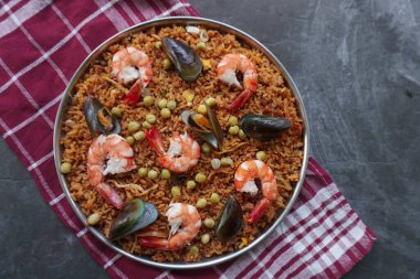 Paella, pirinç, deniz ürünleri, karides, istiridye, limon ve safran soslu bezelye karışımı bir İspanyol yemeğidir..