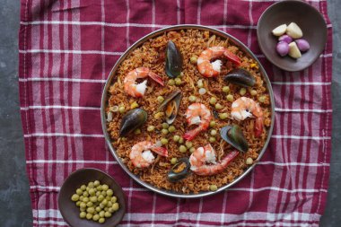 Paella, pirinç, deniz ürünleri, karides, istiridye, limon ve safran soslu bezelye karışımı bir İspanyol yemeğidir..