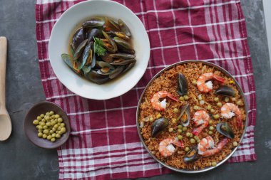 Paella, pirinç, deniz ürünleri, karides, istiridye, limon ve safran soslu bezelye karışımı bir İspanyol yemeğidir..