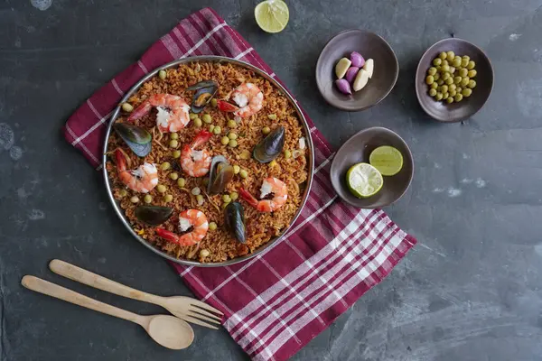 Paella, pirinç, deniz ürünleri, karides, istiridye, limon ve safran soslu bezelye karışımı bir İspanyol yemeğidir..