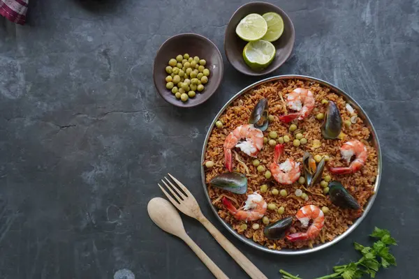 Paella, pirinç, deniz ürünleri, karides, istiridye, limon ve safran soslu bezelye karışımı bir İspanyol yemeğidir..