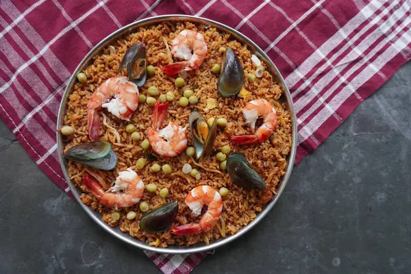 Paella, pirinç, deniz ürünleri, karides, istiridye, limon ve safran soslu bezelye karışımı bir İspanyol yemeğidir..