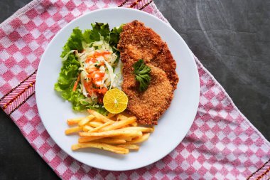 Tavuk şnitzel tavuk göğsünden yapılır, patates kızartması, limon, sebze salatası ve sos ile servis edilir, tabakta mayonez. düz yat