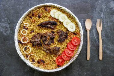 Geleneksel kebuli pilavı, aromatik baharatlı pirinç yemeği, taze et, kuru üzüm, salatalık, soğan, baharat ve taze domates dilimleri ile servis edilir.