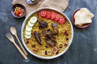 Geleneksel kebuli pilavı, aromatik baharatlı pirinç yemeği, taze et, kuru üzüm, salatalık, soğan, baharat ve taze domates dilimleri ile servis edilir.